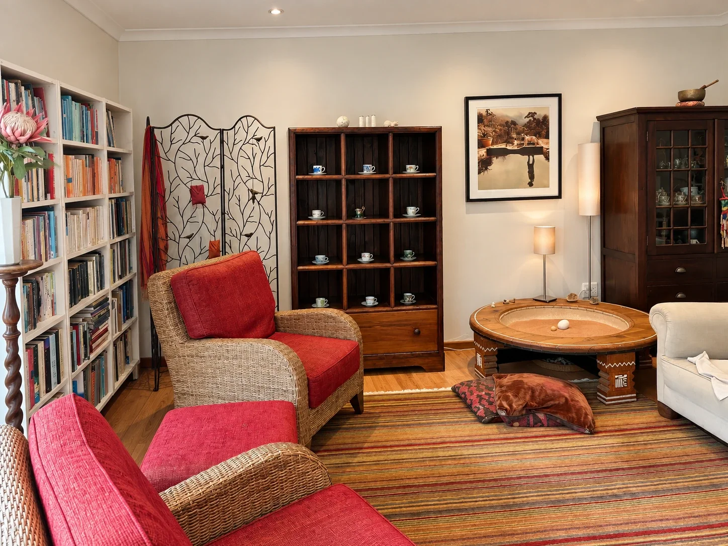 A wider view of the Cape Town counselling room, with red chairs, a sofa and wooden bookshelves