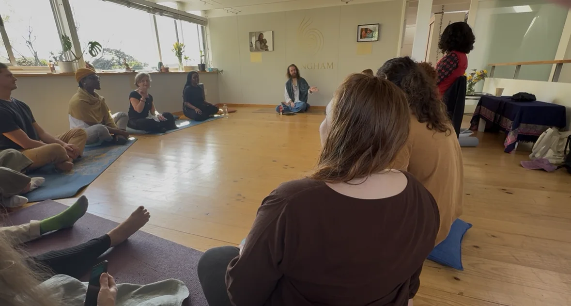 Participants seated on the floor in a Sangham group session, listening as the facilitator speaks